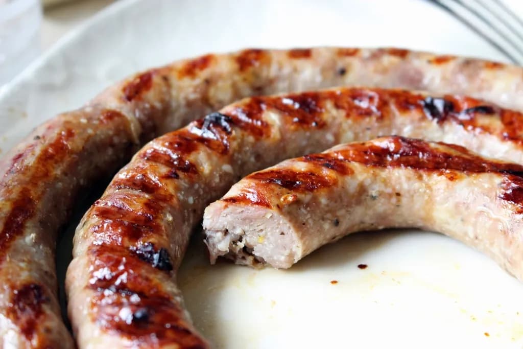 Chorizo con Arepa: Dos chorizos asados al carbón con arepa de maíz, limón y ají de la casa. El clás