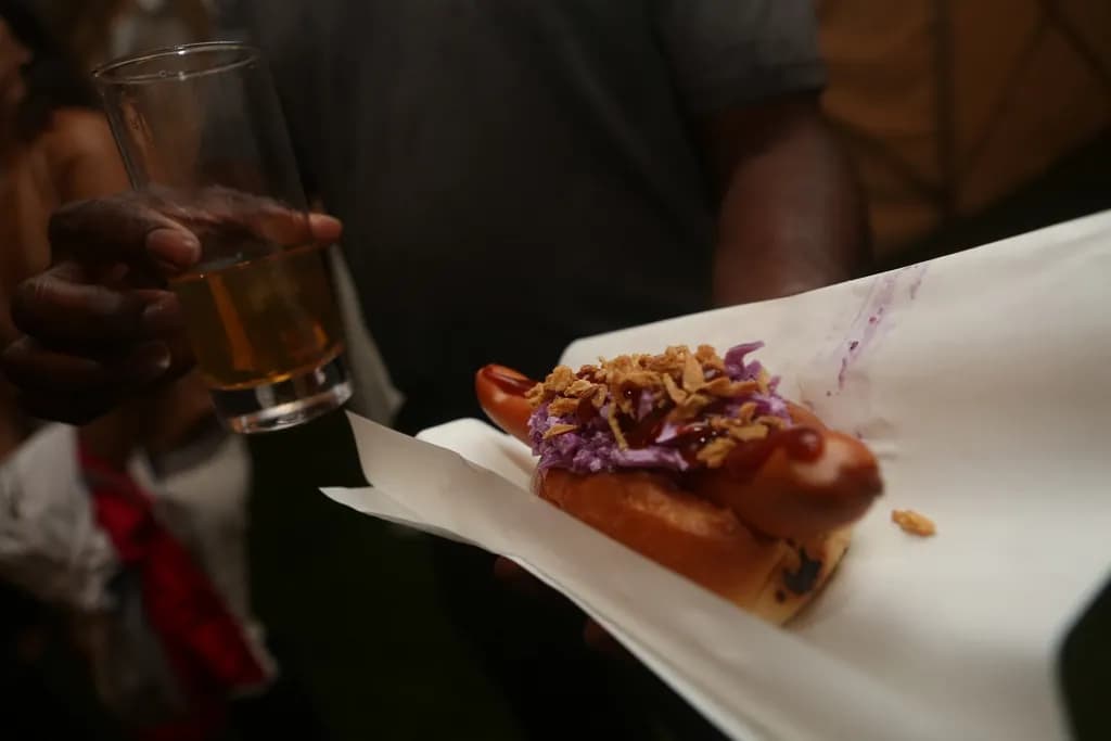 Perro Ranchero: Salchicha ranchera, repollo morado, cebolla crispy, pepinillos y salsa BBQ. Croc