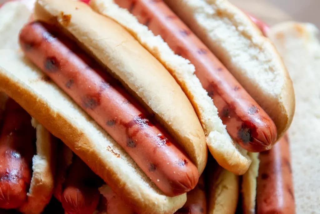 Perro Americano: Salchicha a la parrilla con su marquita, tocineta crocante, queso cheddar fundid