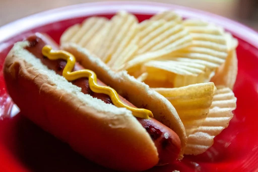 Perro Clásico: Salchicha americana en pan suave con papita triturada, cebolla, salsas de la cas
